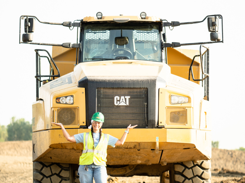 Crew Member Standing In Front Of A Large Dumptruck