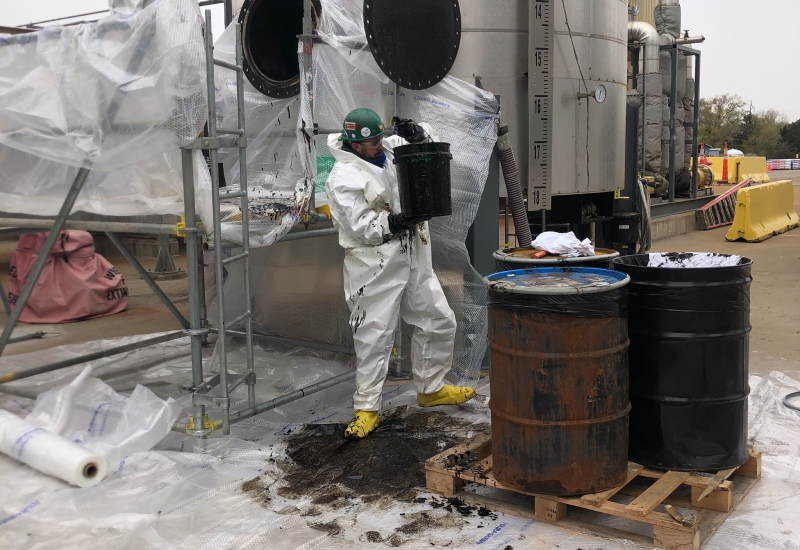 Veit Employee Wearing PPE Kit Lifing Heavy Bucket at an Industrial Cleaning Project