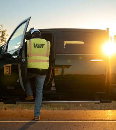 Person in Veit vest enters black pickup at sunset.