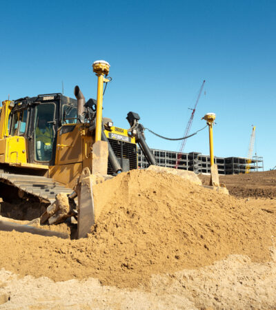 Bulldozer moves dirt at construction site under clear sky.