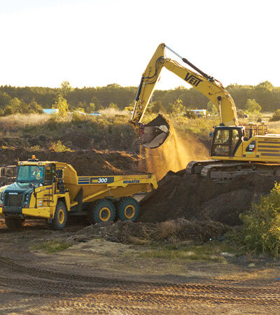 Excavator loading dirt into dump truck at construction site.