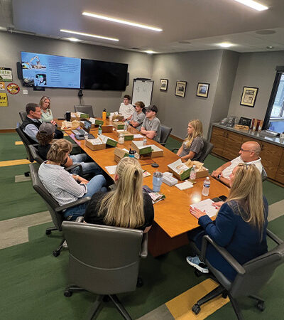 People meeting at a conference table with a screen presentation.