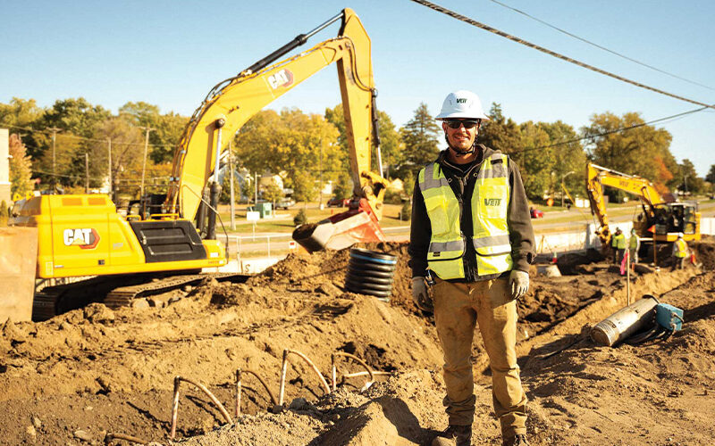 Construction worker in hard hat at site with excavators.