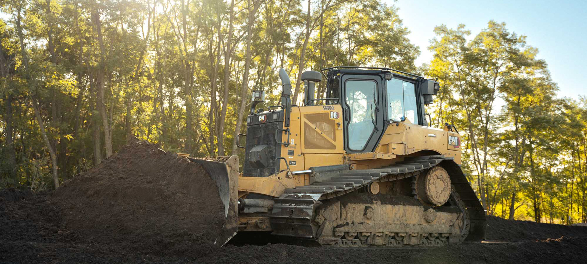 Yellow bulldozer moves soil at sunny construction site.
