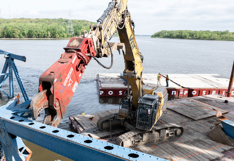 Close-up image of Veit McClugage Bridge project with equipment on barge cutting steal.
